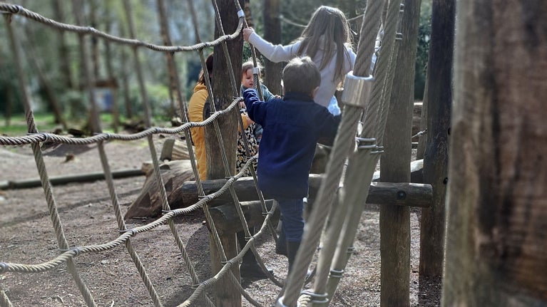 Children climbling on robe bridge with parent and sibling looking on